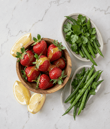 Fresh strawberries with lemon beside parsley-dressed green beans